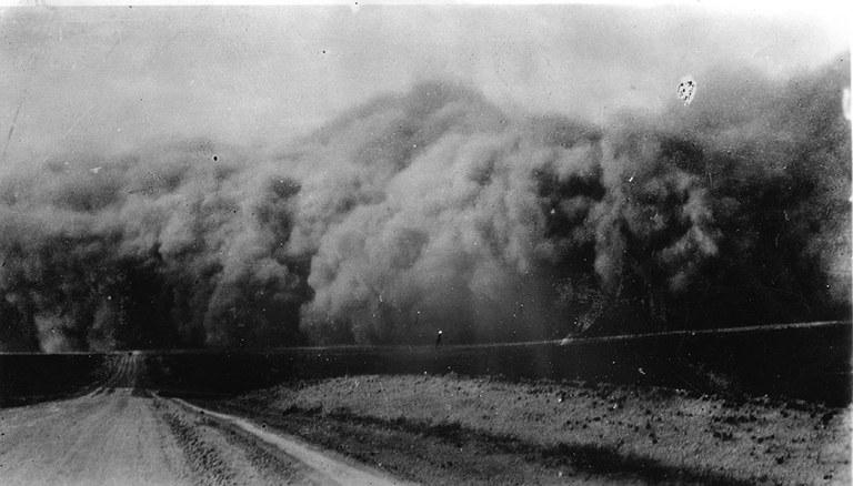 A vintage black and white photo of a dust storm as seen from a dirt road.