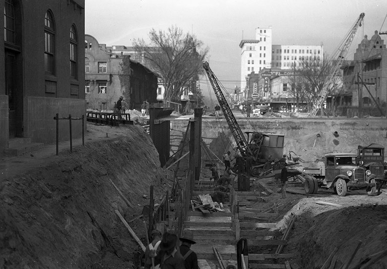 A black and white photo of the Route 66 underpass mid-construction with worker and equipment.