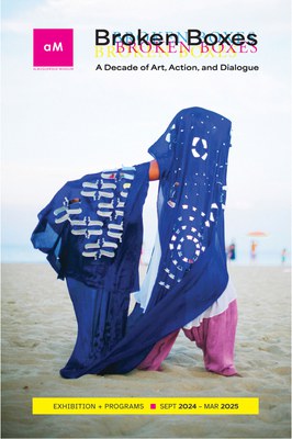 The cover for the Broken Boxes exhibition guide featuring a person in long, flowing blue fabric on the beach.