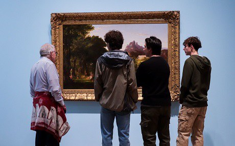 A group of four people reflect on a large painting of a landscape at the Albuquerque Museum.