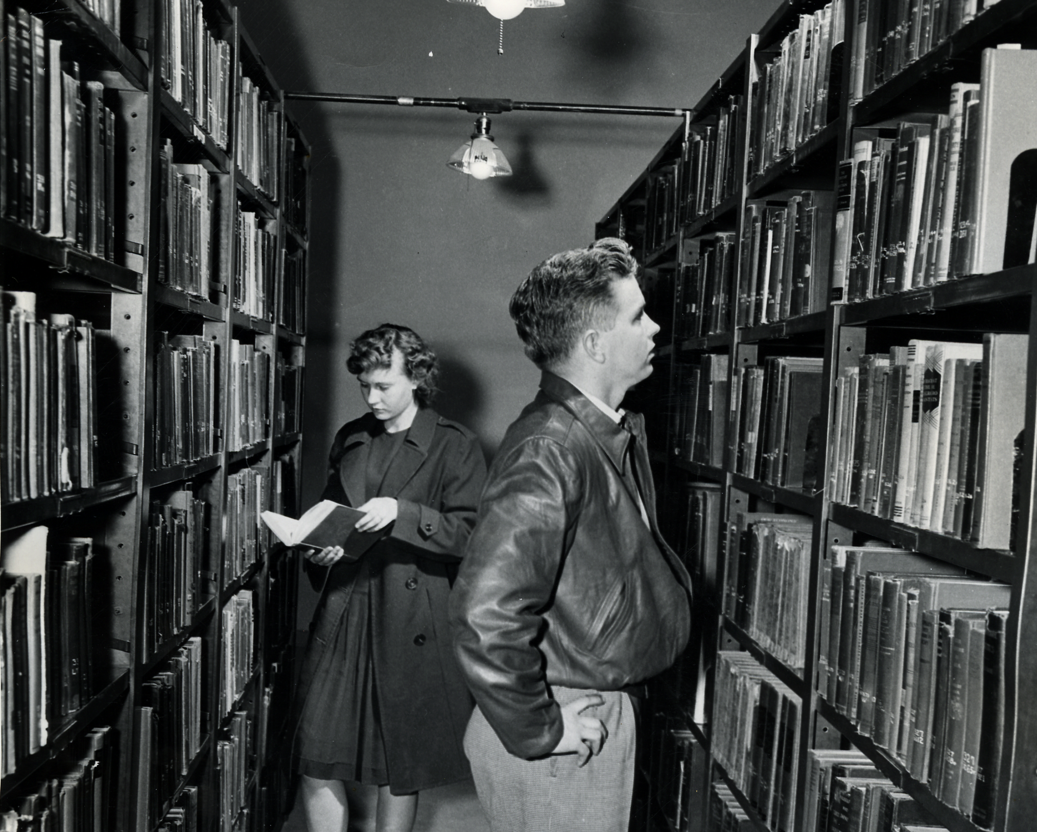 Library with male and female looks at books on shelves