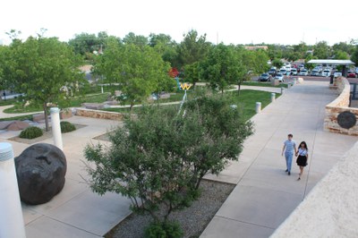 An overhead view of the Sculpture Garden area near the front of the Albuquerque Museum, dotted with trees and lined with concrete pathways and patches of grass and gravel.