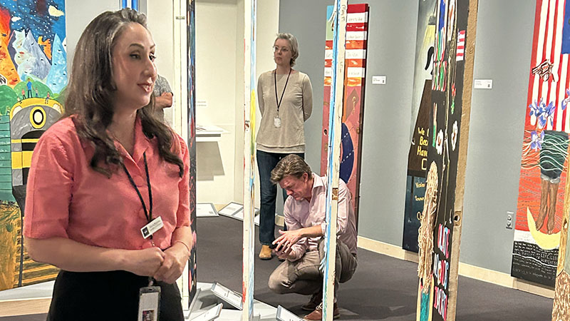 Photograph of a female Museum curator leading a tour in a gallery of painted doors with two other colleagues seen in between the doors.