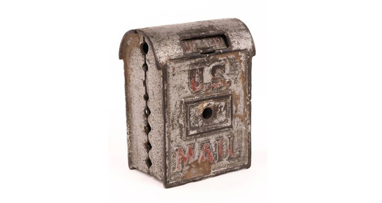 rusted metal container with arched lid at top and "US MAIL" in raised red text on front