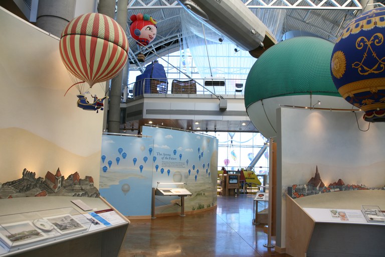 The central lobby of the Balloon Museum featuring several exhibitions with scale model hot air balloons over the centuries.
