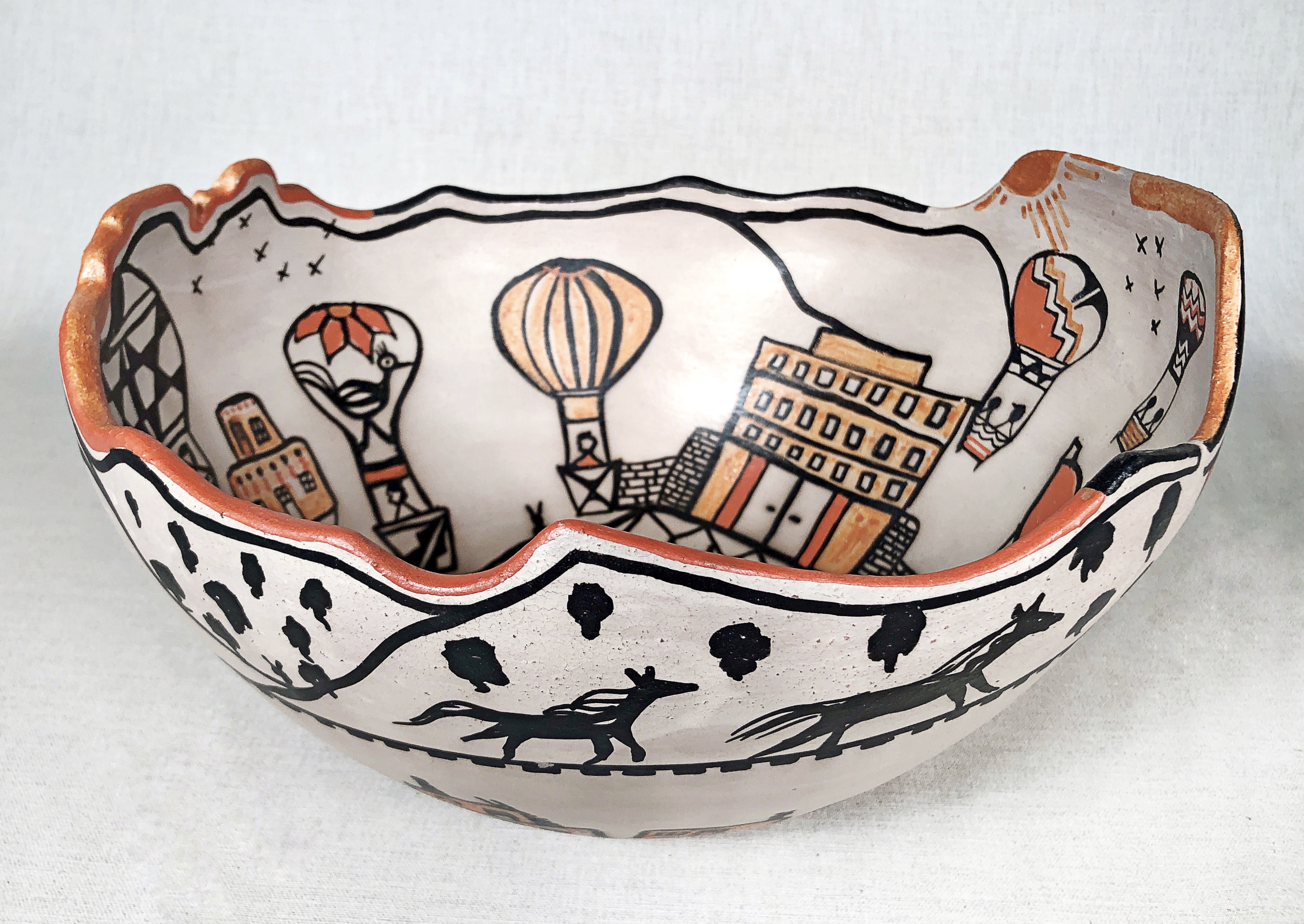 A large ceramic bowl with drawings of balloons and the Sandia Pueblo