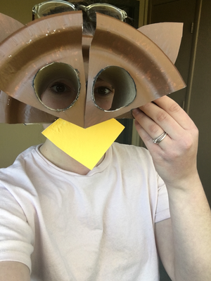 A BioPark staff member models the owl paper craft headpiece project.