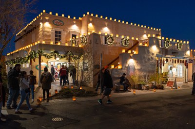 People walking around at night outside of an Old Town shop that is decorated for Christmas.