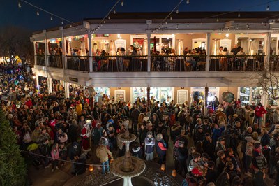 A large crowd filling all of the balcony space on the second story of a building, as well as on the ground.