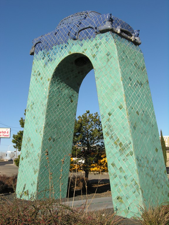 A large-scale, blue ceramic tile monument of a 1954 Chevy atop a large arched pedestal.