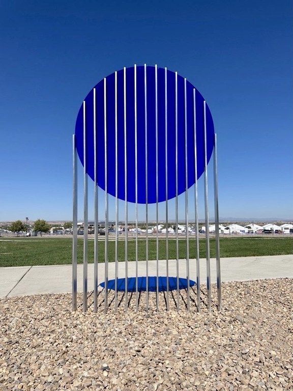 A sculpture featuring a large blue circle sliced into over a dozen segments held up on metal poles.