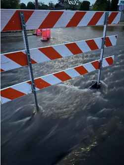 Photo of flooded street with traffic barricade in Pueblo Alto Mile Hi Neighborhood