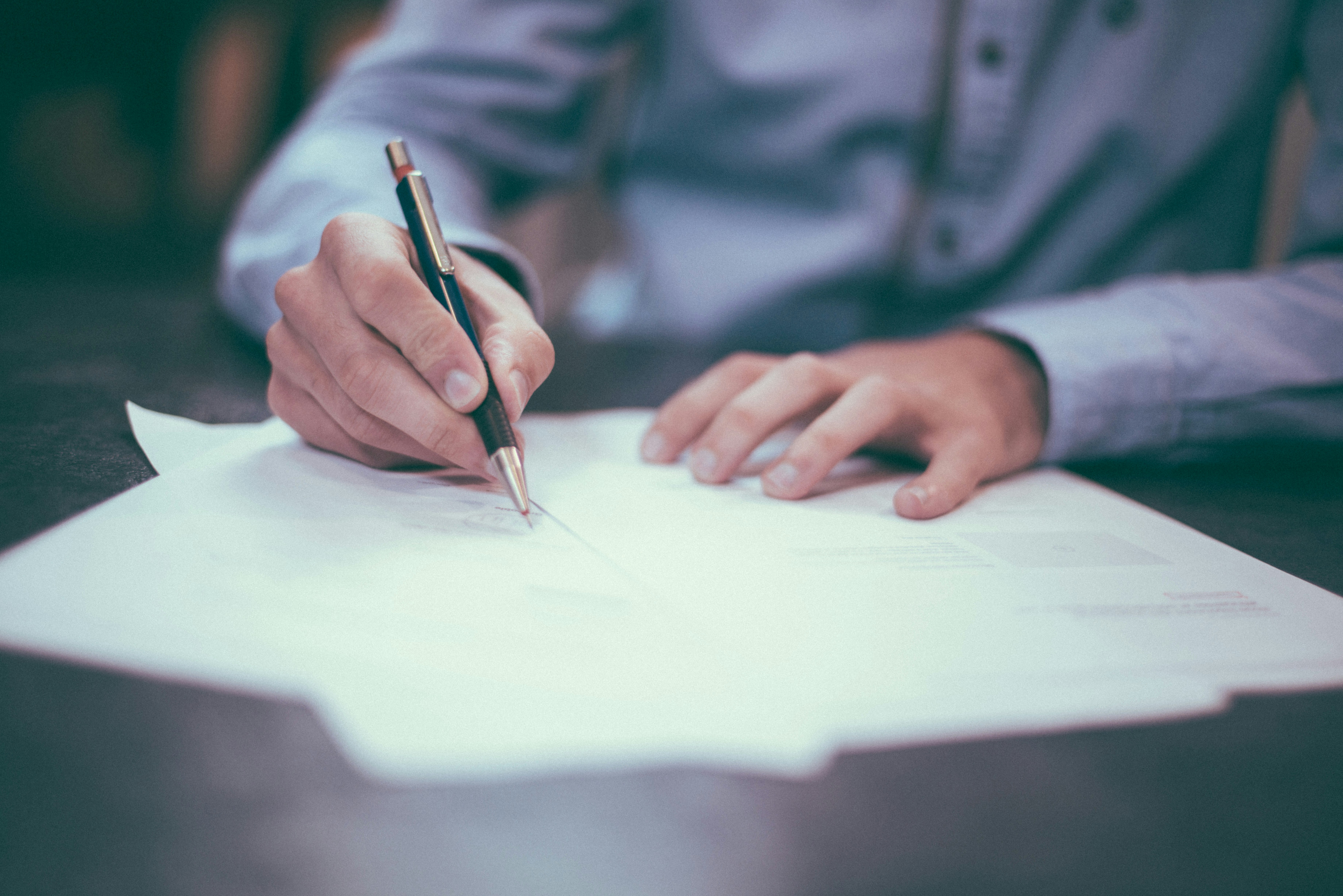 A person signing a document at a table.