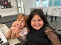 Two children smiling and hugging in a game room of a community center.