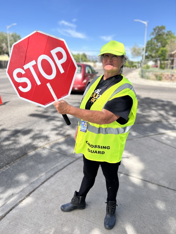 Crossing guard smiling and holding up stop sign