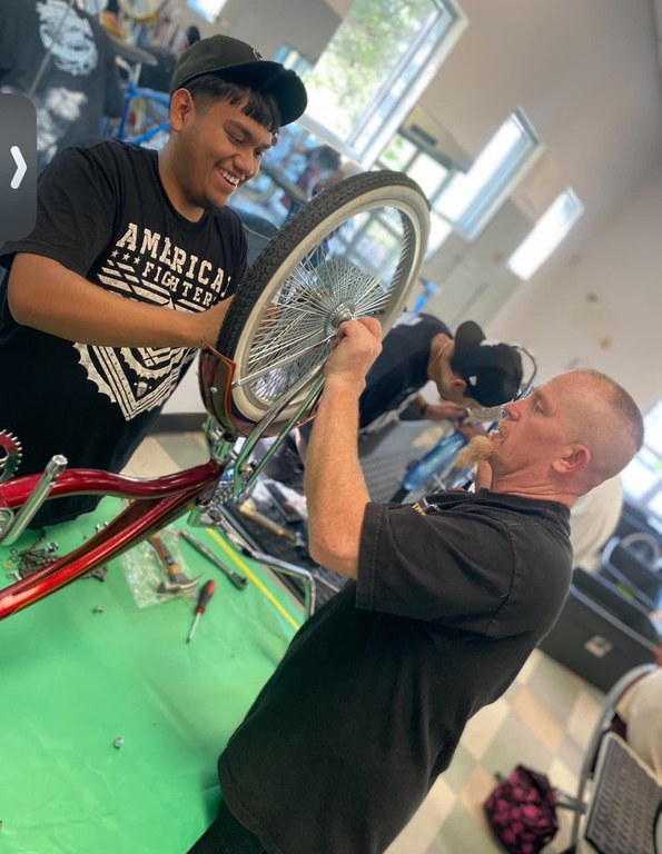 Student building lowrider bike with adult mentor