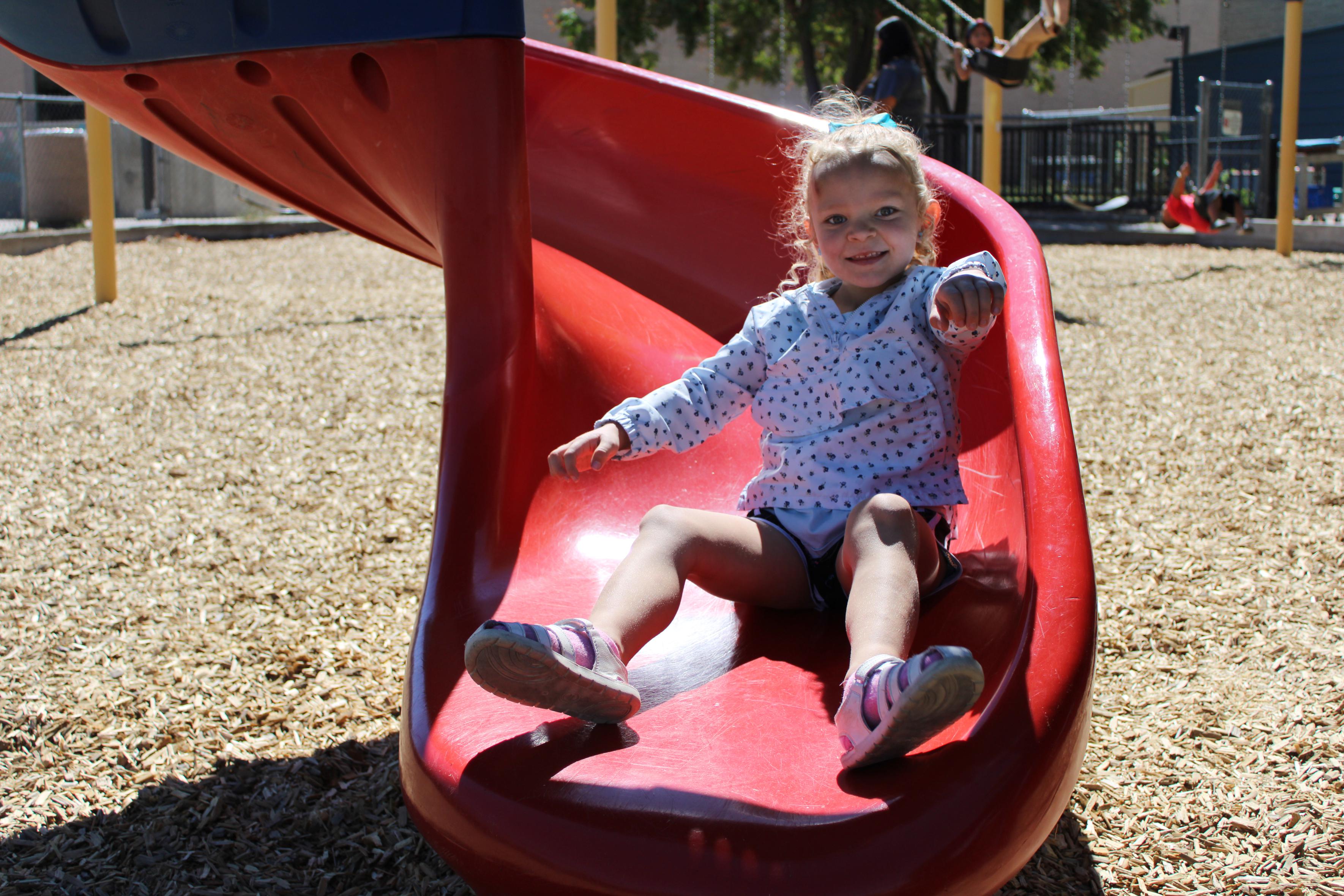 Child smiling at the bottom of the slide