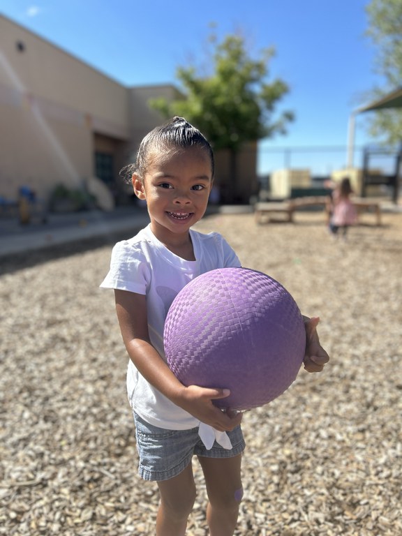 A smiling boy standing on some playground equipment.