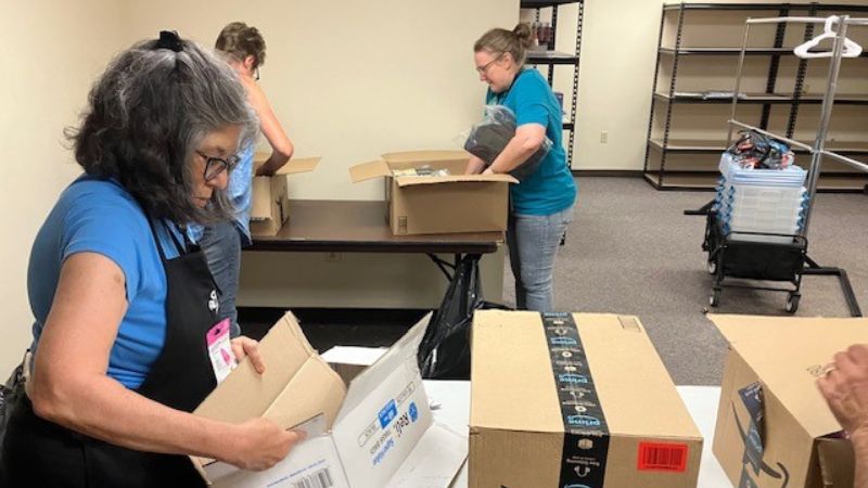 Three people unpacking donated items.