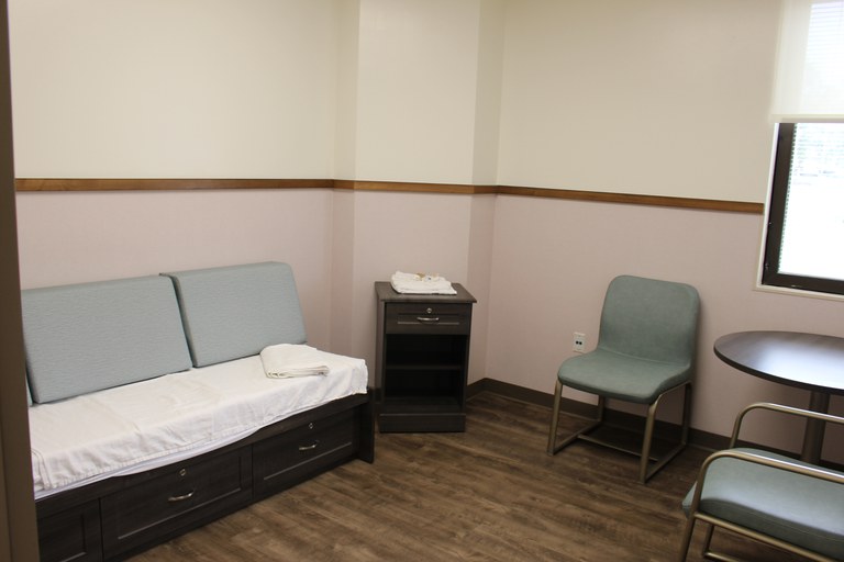 A small room with a convertible bed/couch and a small round table with two chairs.