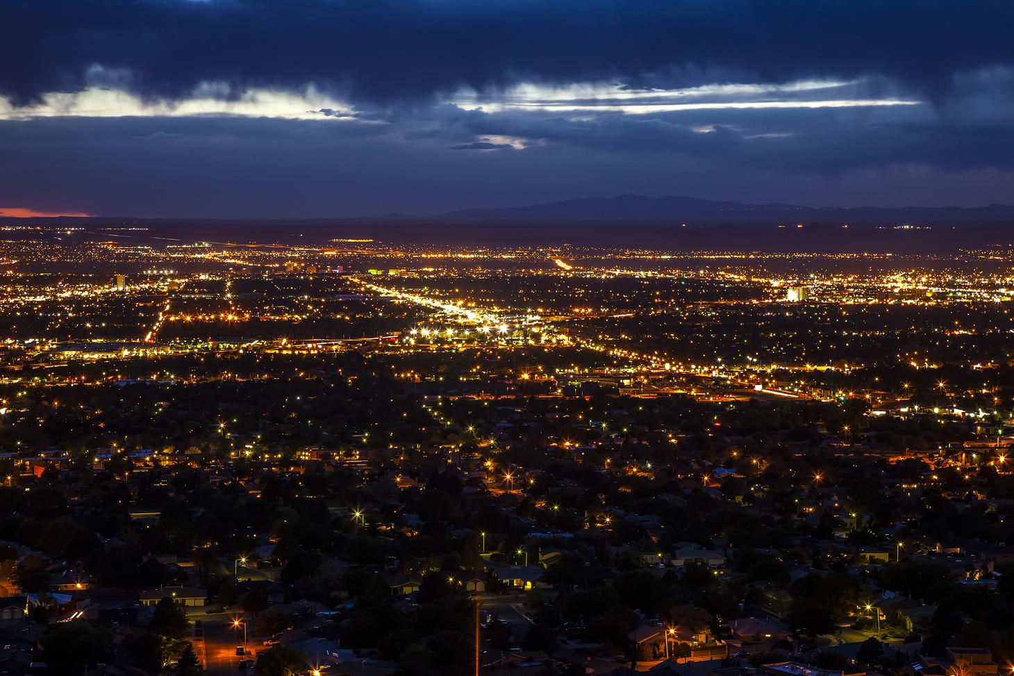 A panorama of street lights in Albuquerque seen from the top of a hill at night.