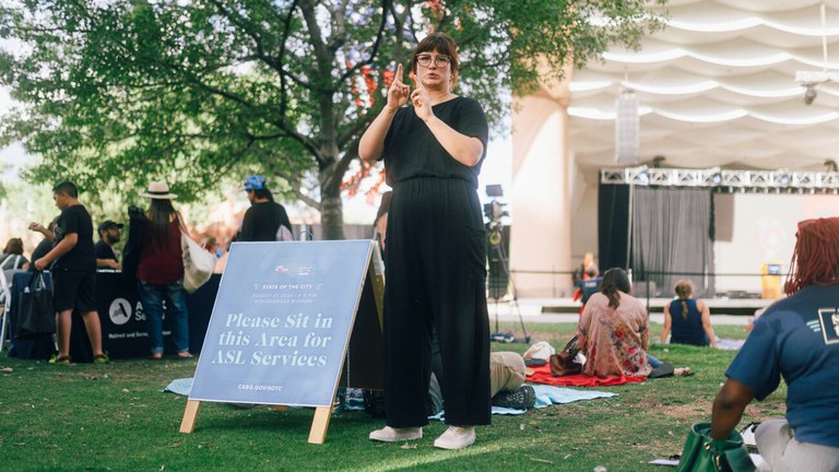 Sign language interpreter in front of a crowd.