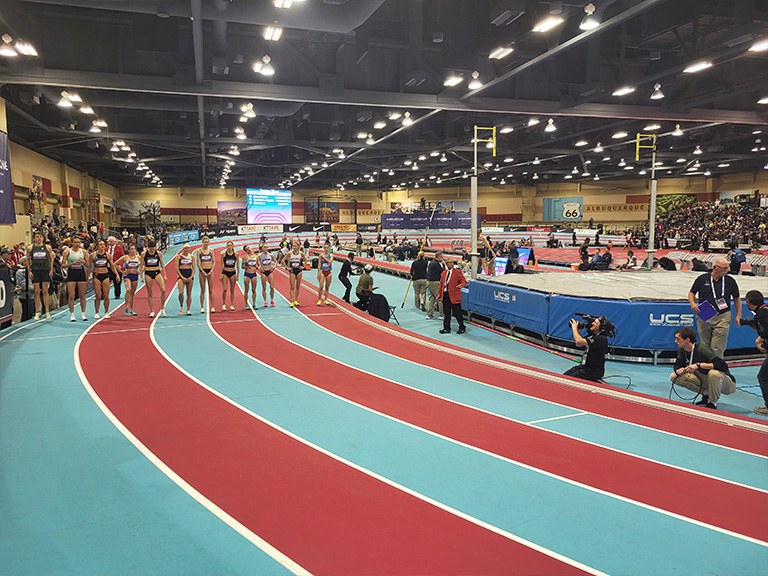 Runners at the start line at an indoor track meet.