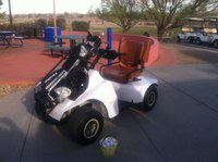 A white golf cart with golf clubs on the front.