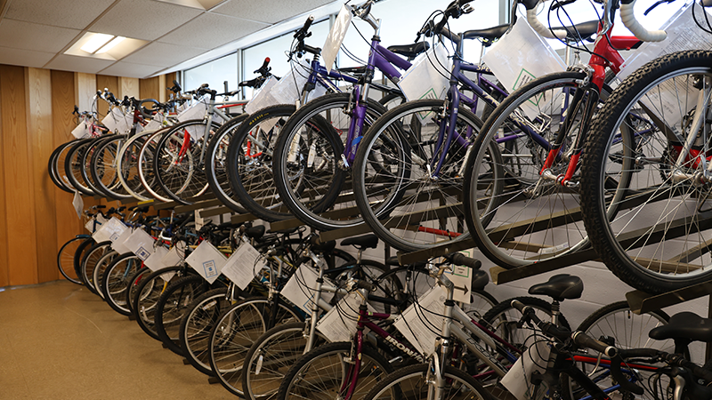 Two rows of bikes with tags on them along a wall.