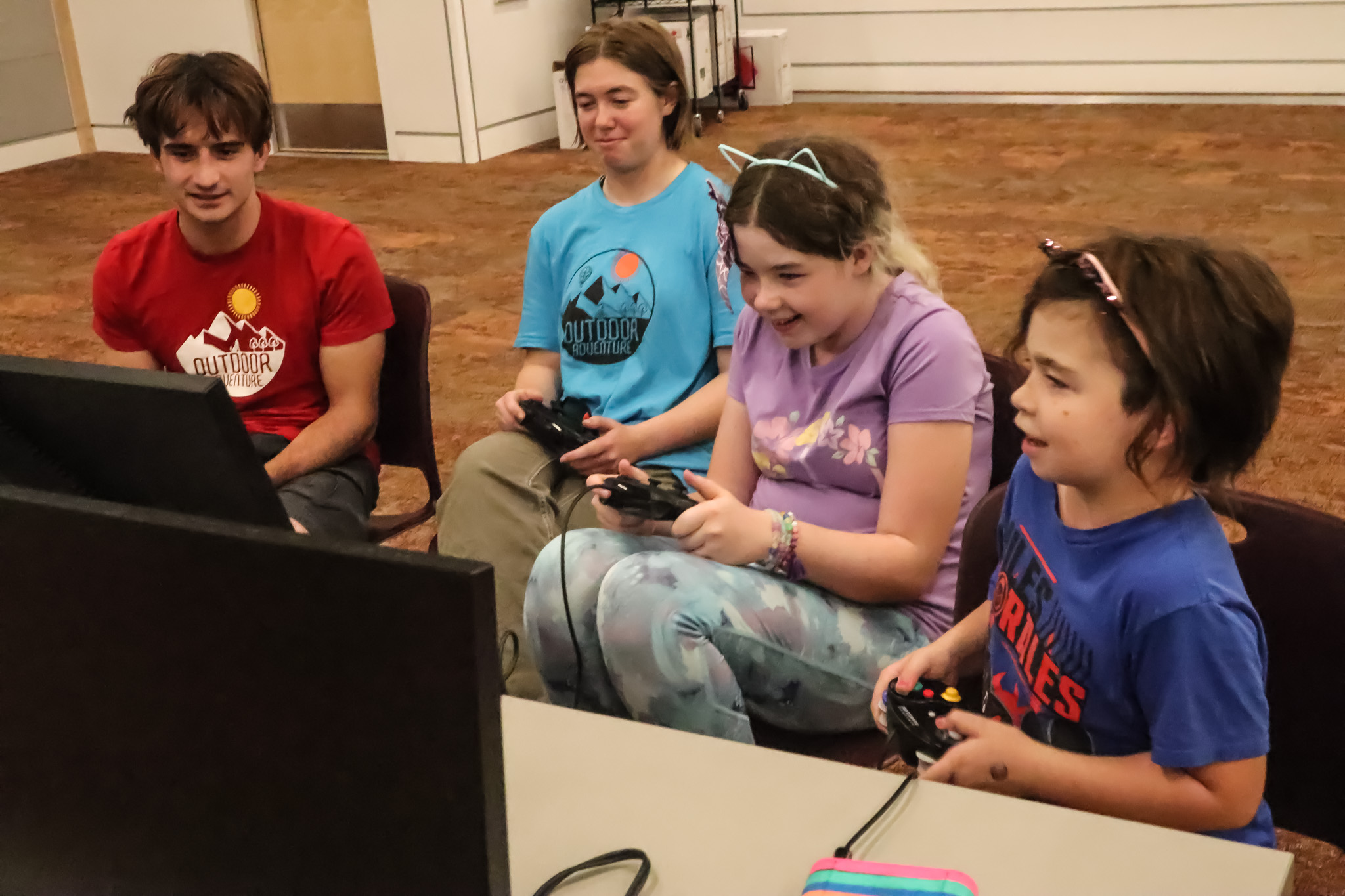 Young child gamers playing teams against Outdoor Adventure staff members.