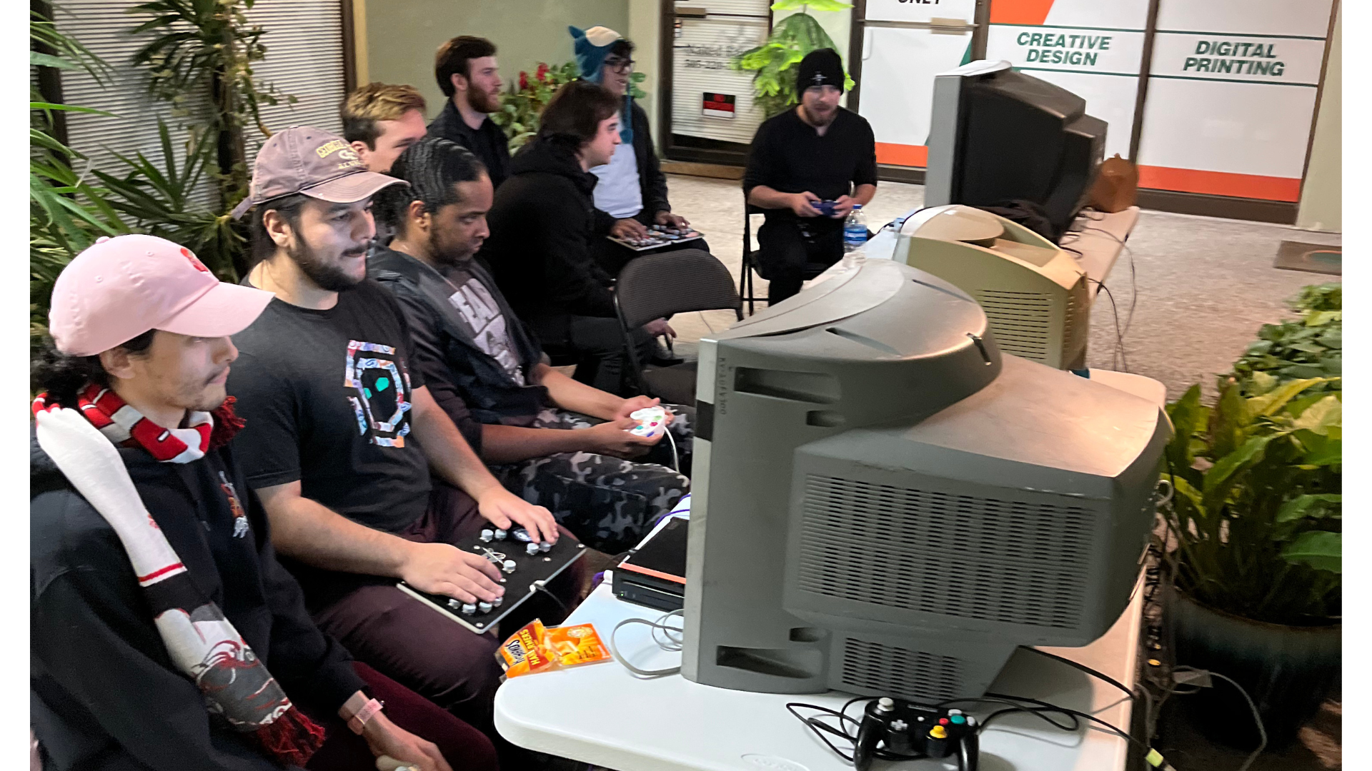 A group of Super Smash Bros Melee players, huddled around a series of tube televisions.