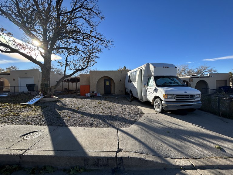 A dilapidated house in need of repair with a white recreational vehicle in the driveway.