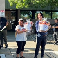 A photo of a smiling young woman and a middle-aged woman volunteering at a Department of Senior Affairs meal site kitchen.